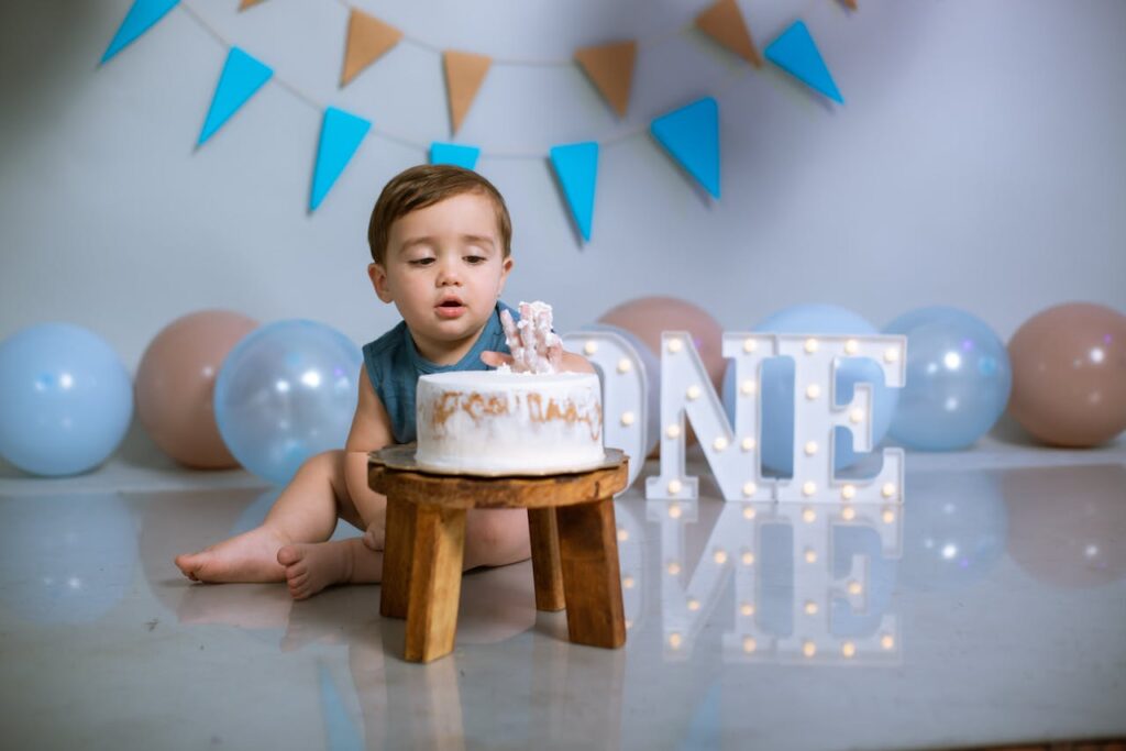 Cute baby enjoying a first birthday cake smash with balloons and decor.